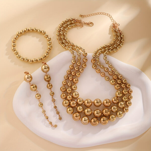 Eclat Newyork's Golden Ball Chain Jewelry Set featuring a layered necklace, bracelet, and drop earrings. With its sleek and stylish design, the set is ideal for events and gatherings.