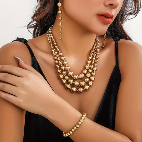 Eclat Newyork's Golden Ball Chain Jewelry Set featuring a layered necklace, bracelet, and drop earrings. With its sleek and stylish design, the set is ideal for events and gatherings.